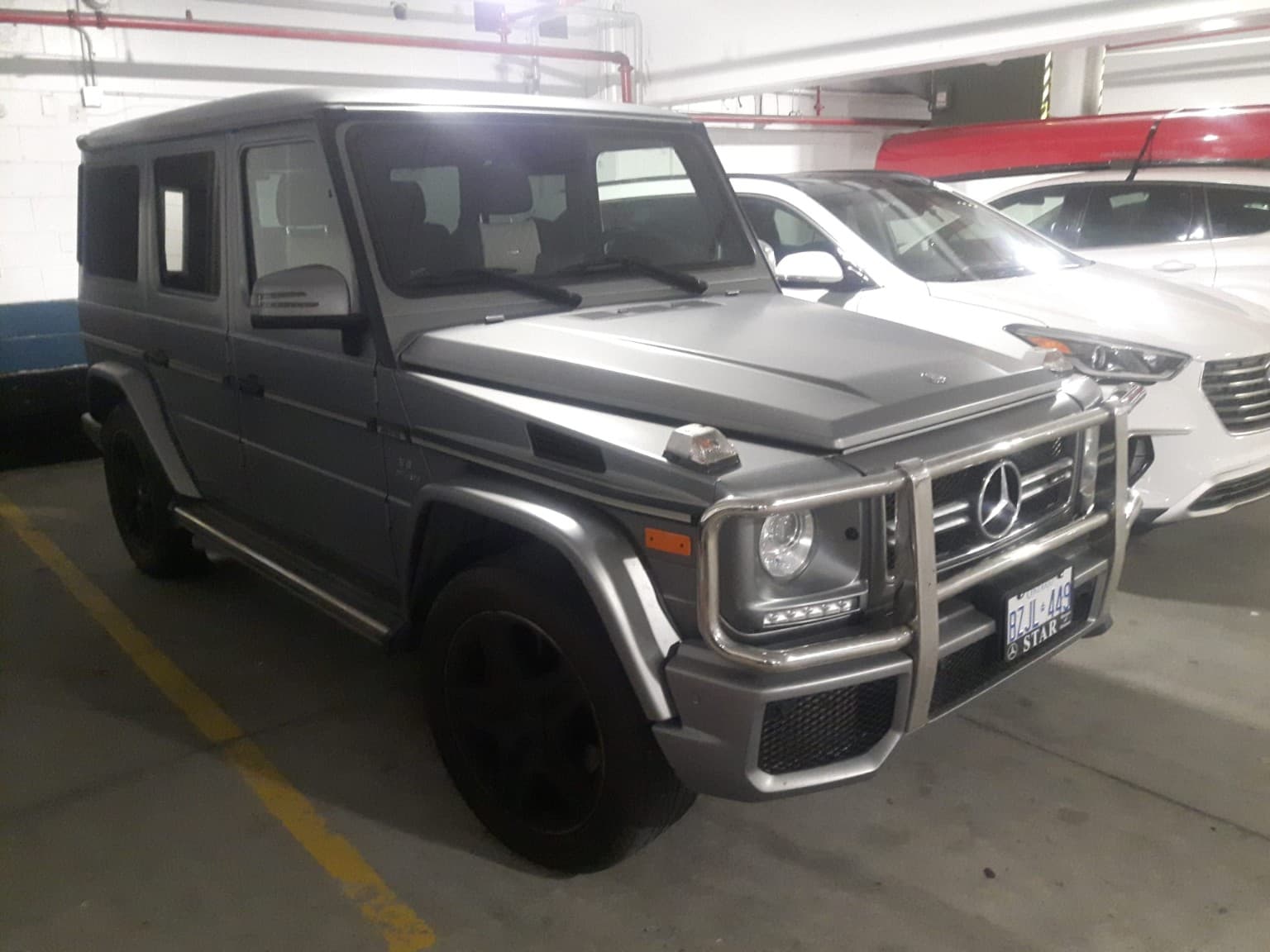 Matte grey Mercedes-Benz G-Class SUV with a silver brush guard parked in an indoor garage.